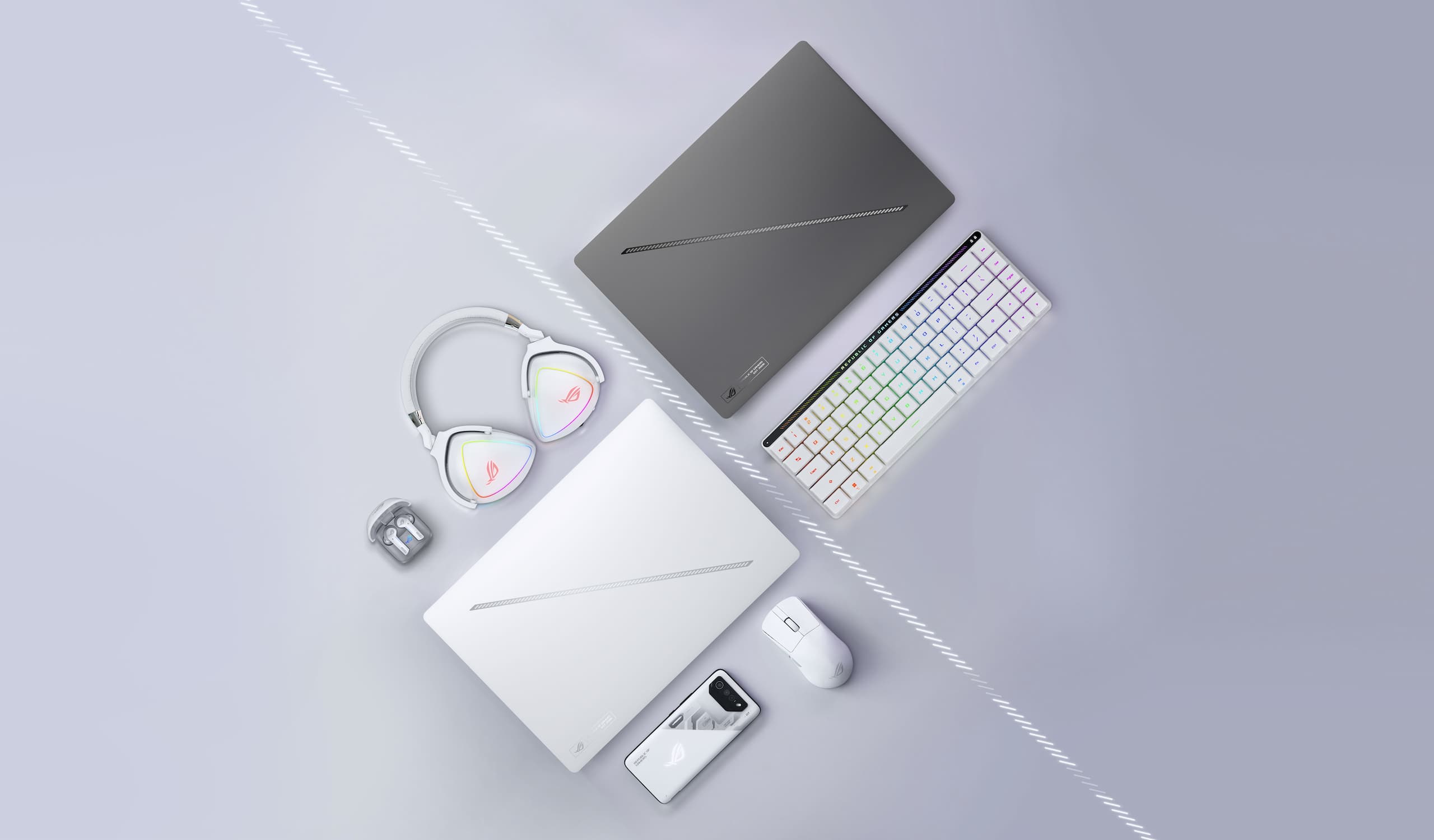 A Platinum White Zephyrus G16, arranged near an ROG mouse, carrying case, and its power adapter.